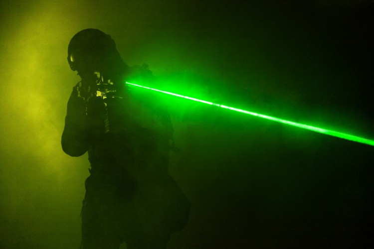 Police officer SWAT in black uniform in the smoke with laser sights